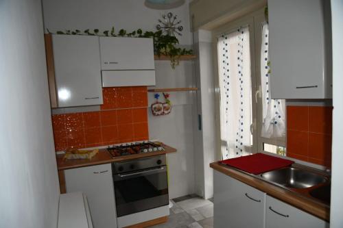 La cuisine est équipée de placards blancs, d'un évier et d'une cuisinière. dans l'établissement La Casa di Ermelinda, à Sapri