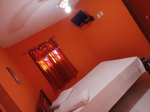 a bedroom with orange walls and a bed with a window at Pousada Betel - Moradas Familia Betel in Salvador