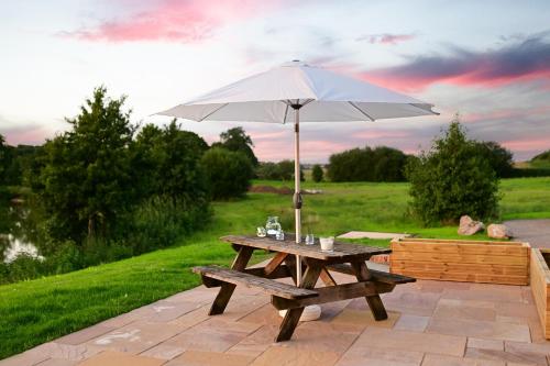 a picnic table with an umbrella on a patio at Cuddfan Lodge on a Beautiful Lake in Newport