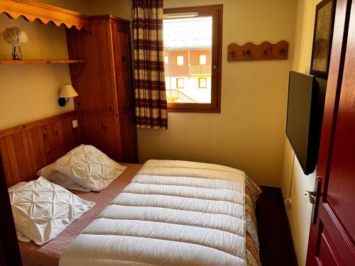 a small bedroom with a bed with a window at Les Alpages location appartement 202 in Lanslebourg-Mont-Cenis