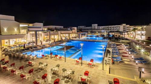 Amarina Abu Soma Resort & Aquapark في الغردقة: مسبح كبير بالطاولات والكراسي في الليل