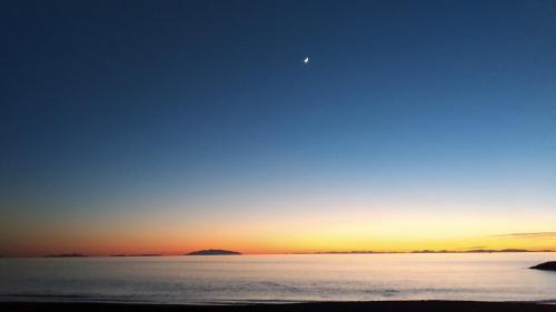 a sunset over the water with the moon in the sky at Lucas House in Bibbona