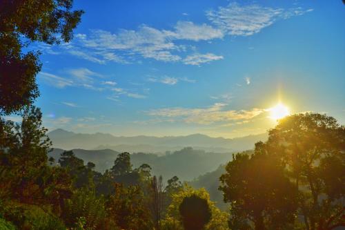 a view of a valley with the sun in the sky at Rainbow Sky Cottage in Ella