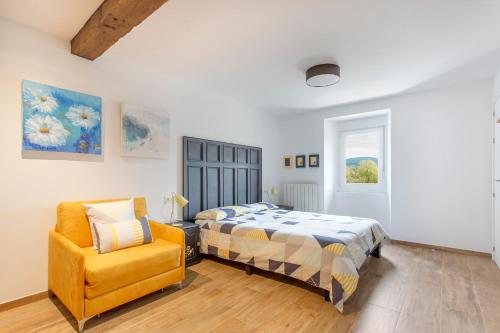 1 dormitorio con 1 cama y 1 silla amarilla en Apartamentos turísticos Rurales ITURBURUARENA, en Alcoz
