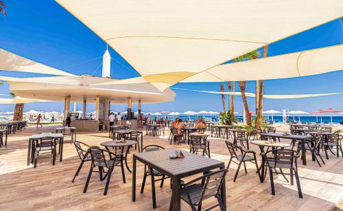 a restaurant with tables and chairs on the beach at Amarina Abu Soma Resort & Aquapark in Hurghada