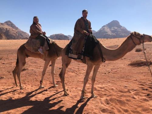 two men riding on a camel in the desert at RUM STARDUST lUXURY CAMP in Wadi Rum