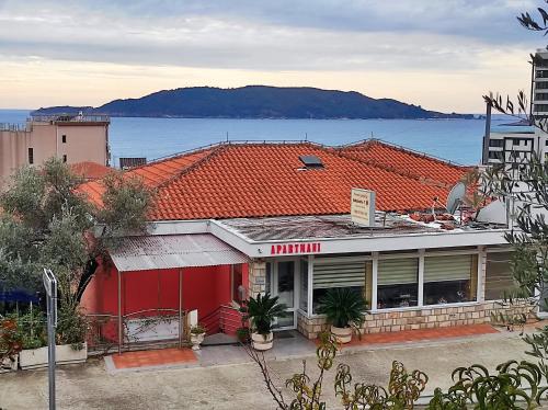 a red building with a red roof next to the water at Villa Aleksandra - T in Rafailovici