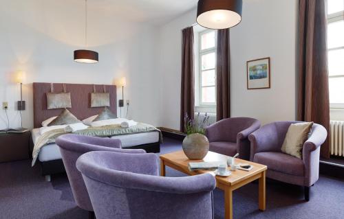 ein Hotelzimmer mit einem Bett und Stühlen in der Unterkunft Hotel Lekker in Neumagen-Dhron