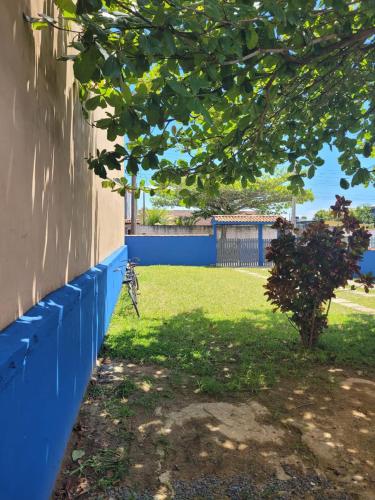a blue fence next to a yard with a tree at Temporada no Paraíso in Ilha Comprida