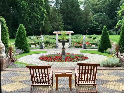 two chairs and a table in a garden with a fountain at Amsterdamgarden - stunning garden villa with pool close to Amsterdam in Laren
