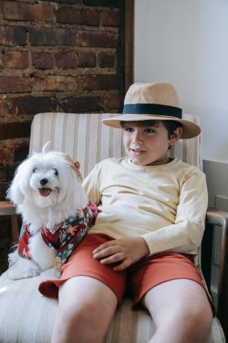 a young boy wearing a hat sitting next to a dog at Econo Lodge Lilydale in Lilydale