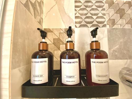 three bottles of soap sitting on a shelf in a bathroom at The Poem Hotel in Mae Pim