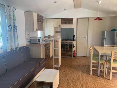 uma sala de estar e cozinha com um sofá e uma mesa em Mobile home à louer 8 personnes em Valras-Plage