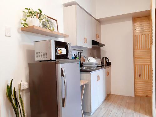 a small kitchen with a refrigerator with a microwave at Mireya's Studio Condo at Goshen Towers - Session Road in Baguio