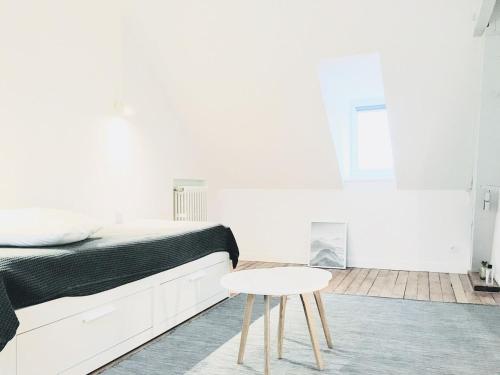 a white bedroom with a bed and a table at Bienvenue chez l'habitant in Provins