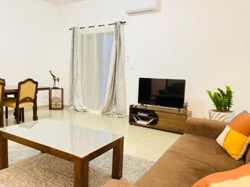 ein Wohnzimmer mit einem Sofa und einem TV in der Unterkunft LeCosy House in Dakar