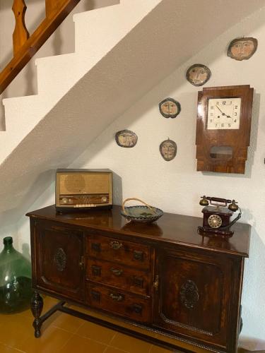 a wooden dresser with a clock and clocks on the wall at Masía Can Janet in Arbúcies