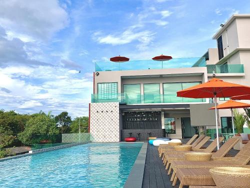 a pool with chairs and umbrellas in front of a building at The Poem Hotel in Mae Pim