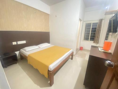 a bedroom with a bed with a yellow blanket at Star Residency in Mysore
