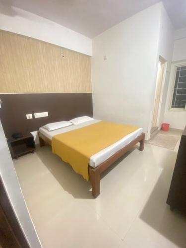 a bedroom with a bed with a yellow blanket at Star Residency in Mysore
