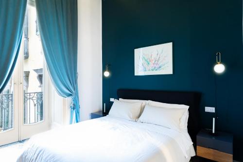 una camera blu con un letto bianco e una finestra di SUITE CASA FANZAGO a Napoli
