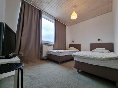 a room with two beds and a tv and a window at Hostel Dharma in Rijeka
