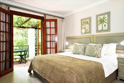 a bedroom with a large bed and a balcony at Rivonia Premier Lodge in Johannesburg