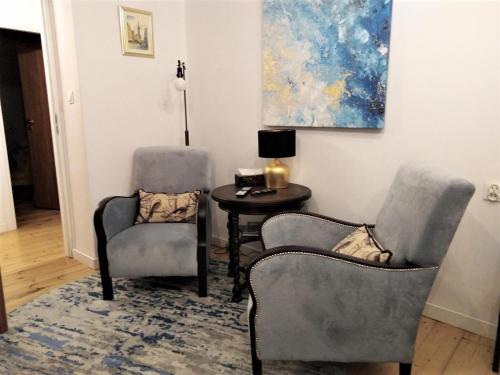 duas cadeiras e uma mesa num quarto com uma pintura em Wygodny Apartament w Śródmieściu Gdańska em Gdansk