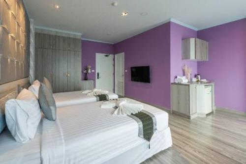 a large bed in a room with purple walls at Napheera Royal Tel in Ban Khlong Bang Krathiam