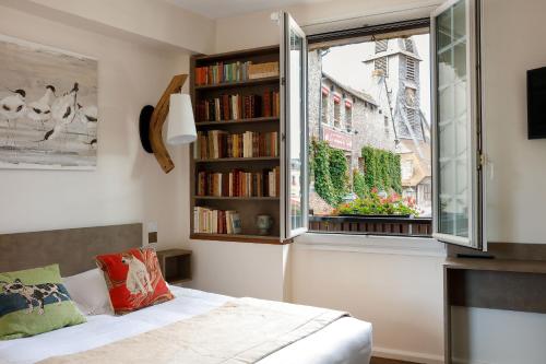a bedroom with a bed and a window with books at Hotel Le Dauphin in Honfleur