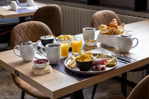 a table with breakfast foods and coffee on it at Hotel Le Dauphin in Honfleur