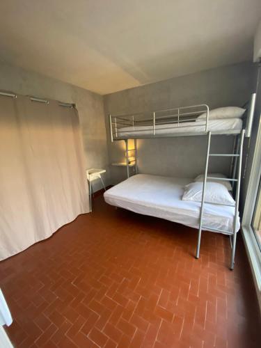 Cette chambre dispose de deux lits superposés et d'un sol en briques. dans l'établissement T3 PLEIN PIED FRONT DE MER, au Barcarès