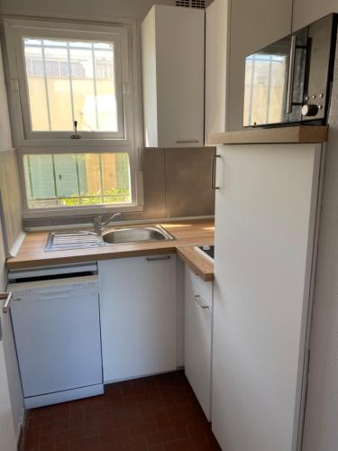 une cuisine avec un réfrigérateur blanc et un évier dans l'établissement T3 PLEIN PIED FRONT DE MER, au Barcarès