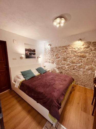 a bedroom with a bed with a stone wall at Guesthouse F in Split