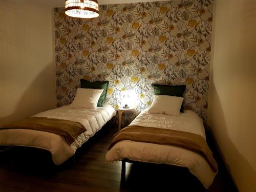 two twin beds in a room with a wall at Le Petit Relais de Launois in Launois-sur-Vence