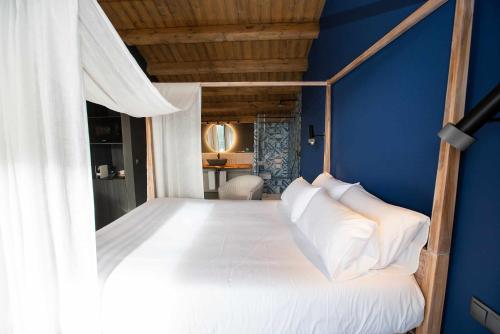 um quarto com uma cama branca e uma parede azul em Mochoruralhome ulldemo suite em Beceite