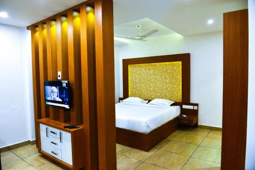 a bedroom with a bed and a tv in it at AURA RESIDENCY in Payyannūr