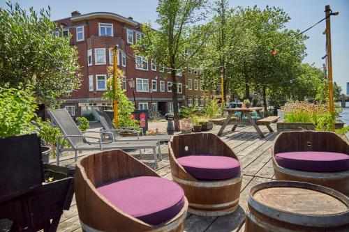 a patio with wooden chairs and tables and a building at The Amsterdam Houseboat Family - de Pijp in Amsterdam