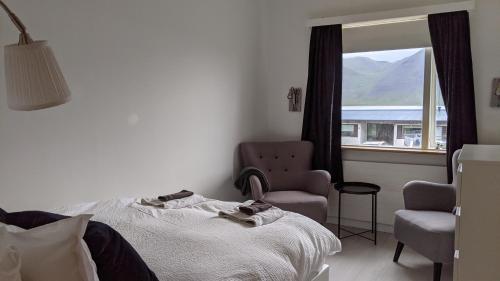 ein Schlafzimmer mit einem Bett, einem Stuhl und einem Fenster in der Unterkunft Flateyri guesthouse in Flateyri