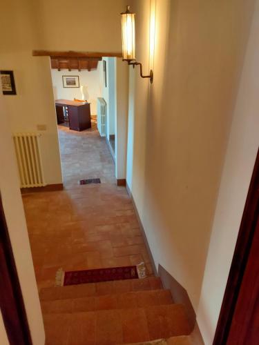 a hallway with a staircase with a light on the wall at Palazzo Bianciardi Attico in Castellina in Chianti