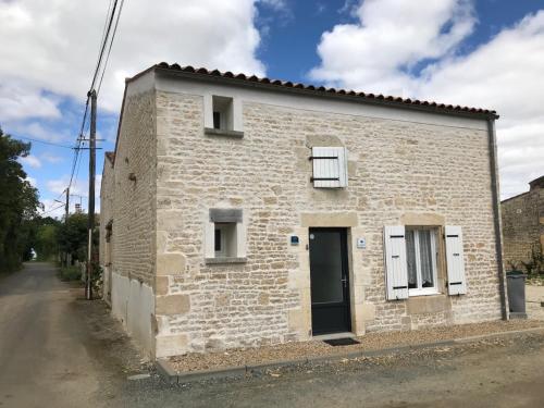 ein kleines weißes Backsteinhaus mit einer schwarzen Tür in der Unterkunft Essai de chaille in Surgères