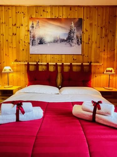 a bedroom with a large bed with red sheets and towels at Case Vacanza Perron in Sauze dʼOulx