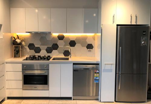 a kitchen with white cabinets and stainless steel appliances at La Sky Boutique Apartment - Pool, Spa & Sauna in Melbourne