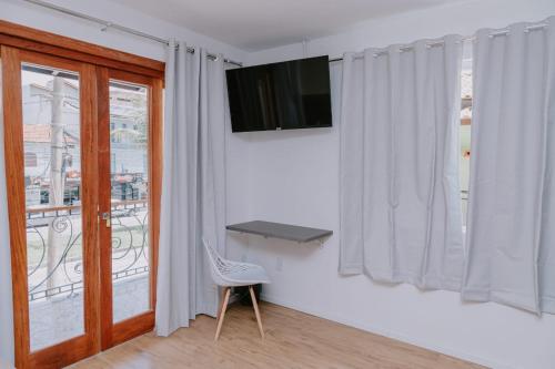 a room with a window with a chair and a television at Pousada Velas do Forte in Cabo Frio