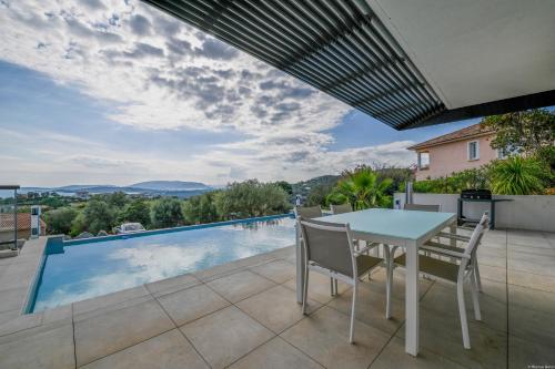 un patio avec une table et des chaises et une piscine dans l'établissement Villa neuve et luxueuse vue mer proche Portovecchio, à Zonza