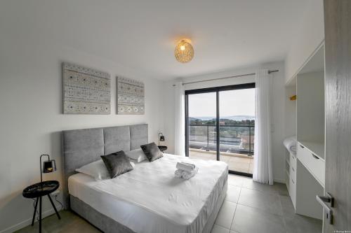 une chambre blanche avec un grand lit et une fenêtre dans l'établissement Villa neuve et luxueuse vue mer proche Portovecchio, à Zonza