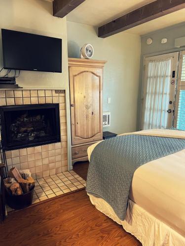 a bedroom with a bed and a fireplace and a tv at Carmel Garden Inn in Carmel