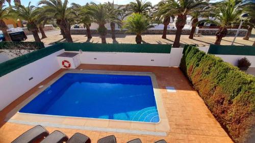 a large swimming pool on a patio with palm trees at Villa Lorena in Sa Caleta