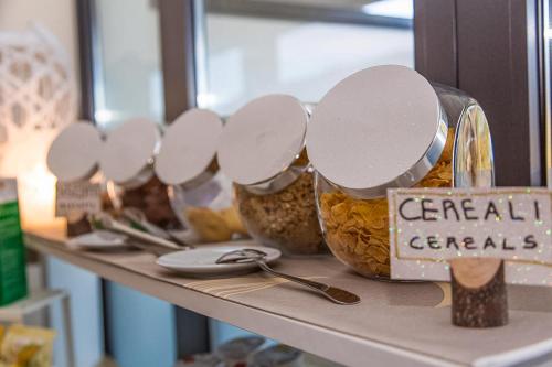 a shelf with several jars of cereal cereals and spoons at Hotel Chalet del Lago in Avigliana