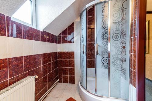 y baño con ducha y azulejos rojos. en Pension ASTORIA, en Klášterec nad Ohří